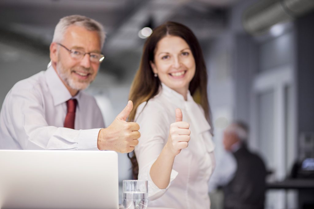 smiling successful businesspeople showing thumb up sign office