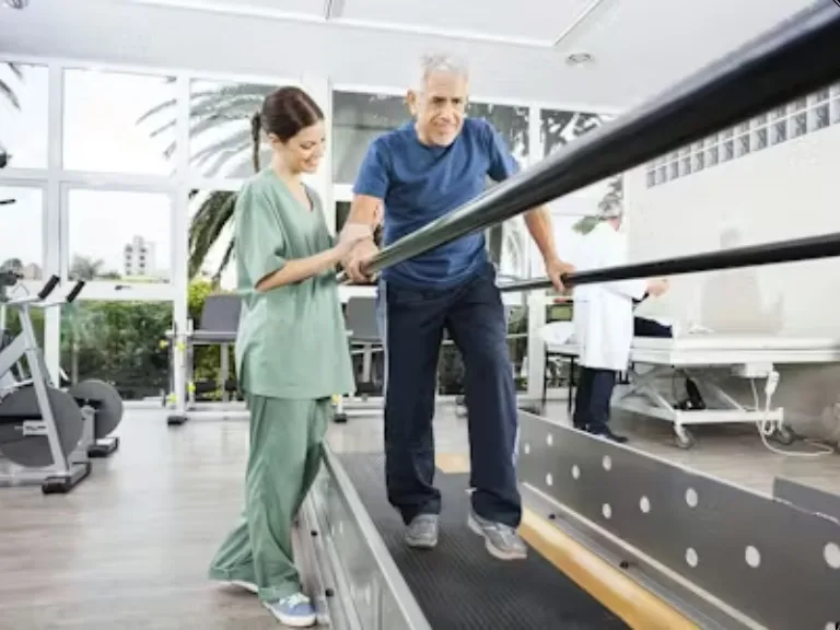 Physical therapist assisting an older man as he walks between parallel bars during rehabilitation therapy